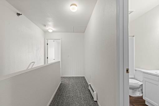 A long, narrow hallway with a carpeted floor and white walls.