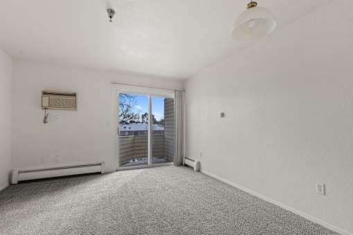 A spacious, empty room with a sliding glass door leading to a backyard.