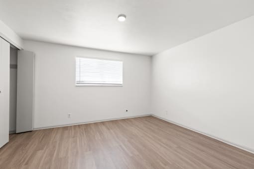 the living room of an apartment with white walls and wood floors