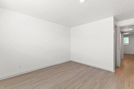 an empty living room with white walls and wood flooring