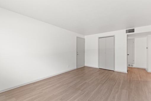 an empty living room with white walls and wood floors