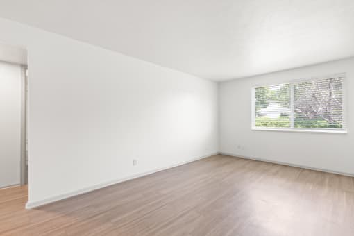the living room of an apartment with white walls and wood floors
