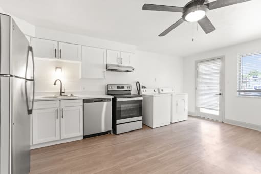 an empty kitchen with white appliances and a ceiling fan