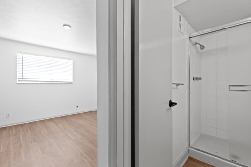 an empty bedroom with a bathroom and a shower