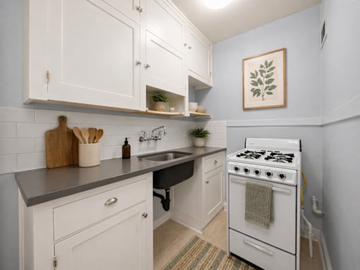 A kitchen with white cabinets and a white stove.