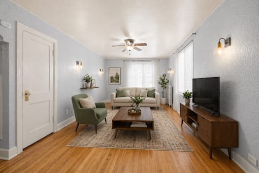 A living room with a green chair, a white sofa, and a wooden coffee table.