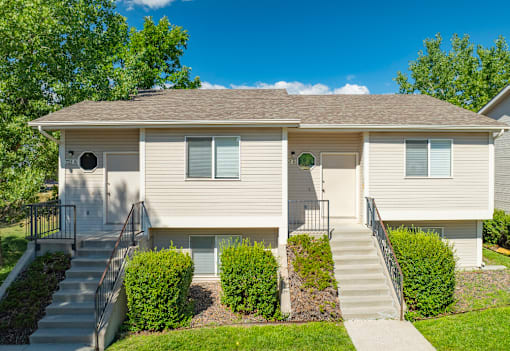 A two-story house with a front yard and stairs leading to the entrance.