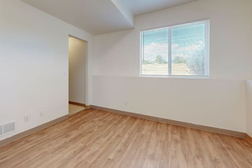 an empty room with wood flooring and a window