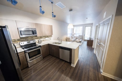 A modern kitchen with stainless steel appliances and wooden floors.