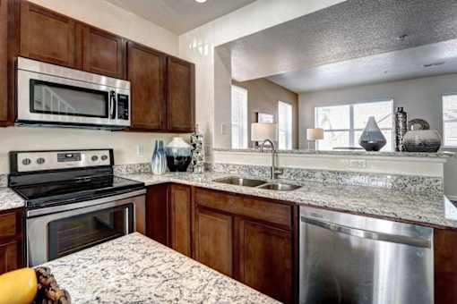 A kitchen with a granite countertop and stainless steel appliances.