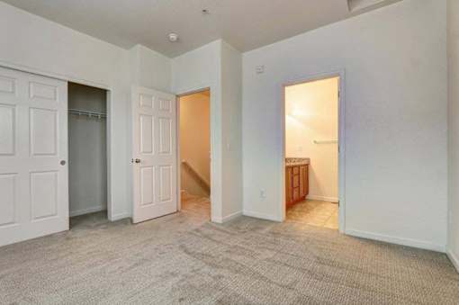 A room with a carpeted floor and white walls with a doorway leading to another room.