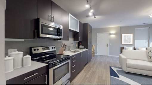 A modern kitchen with dark brown cabinets and stainless steel appliances.at The Logan Apartments, Denver, CO 80203