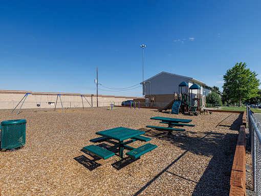 Picnic tables and a trash can are set up on a gravel field.