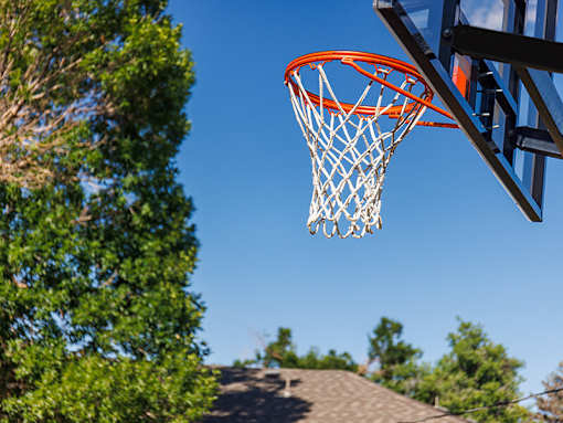 A basketball hoop with a net is seen against a clear blue sky.