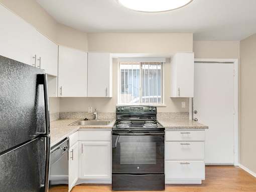 A black stove in a kitchen with white cabinets.