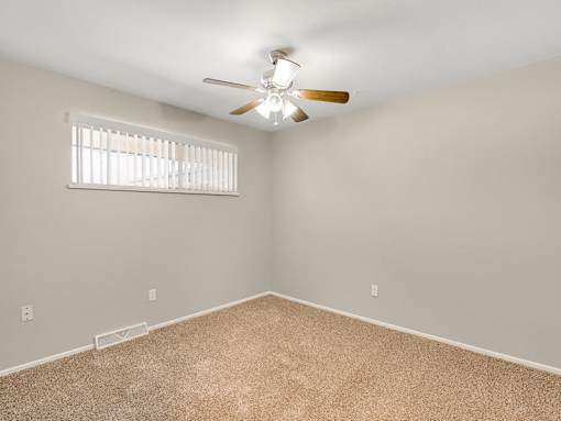 A room with a ceiling fan and carpeted floor.