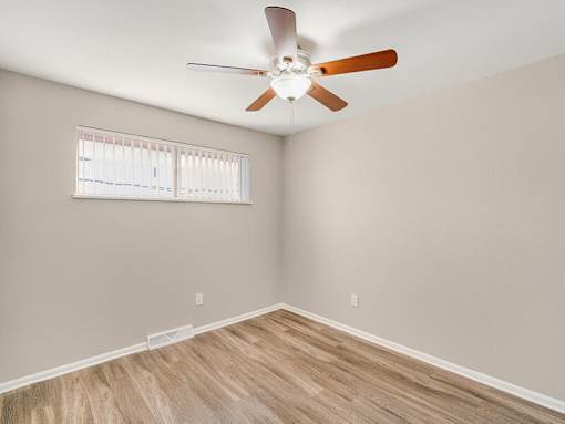 A room with a ceiling fan and a window with blinds.