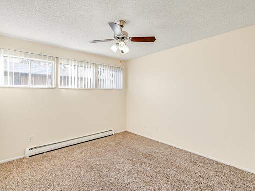 A room with a ceiling fan and a window with blinds.