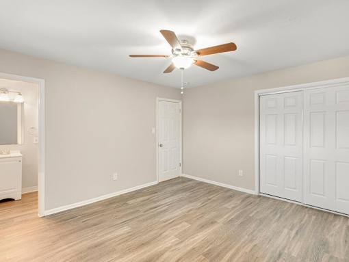 A room with a ceiling fan and wood flooring.
