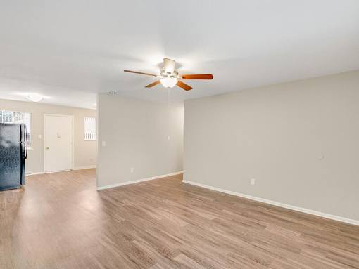 A room with a ceiling fan and wooden flooring.