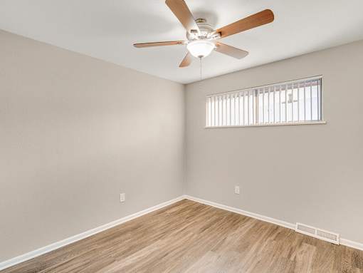 A room with a ceiling fan and a window with blinds.