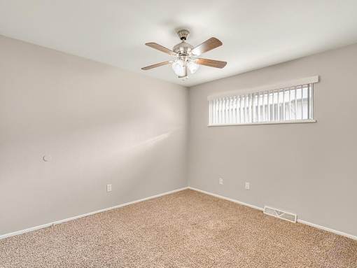 A room with a ceiling fan and a window with blinds.