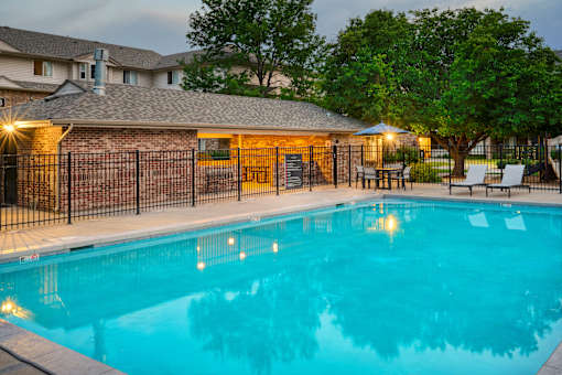 A pool surrounded by a black fence and a building in the background.