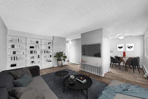 A living room with a grey couch, a black coffee table, and a bookshelf filled with books.