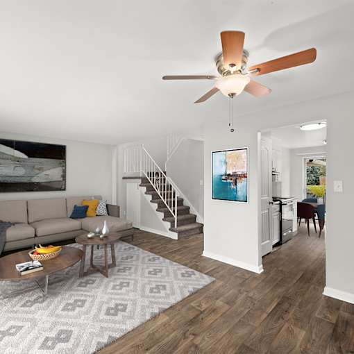 A living room with a brown ceiling fan and a grey rug.
