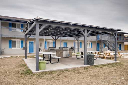 A patio area with a table and chairs is covered by a metal roof.