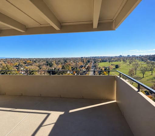 A balcony overlooks a cityscape with a clear blue sky.