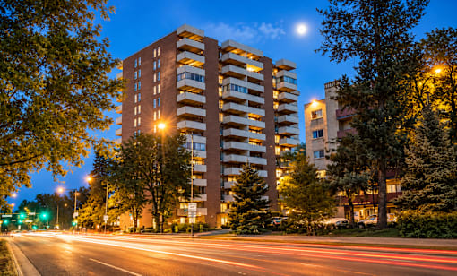 A tall building with a balcony is lit up at night.