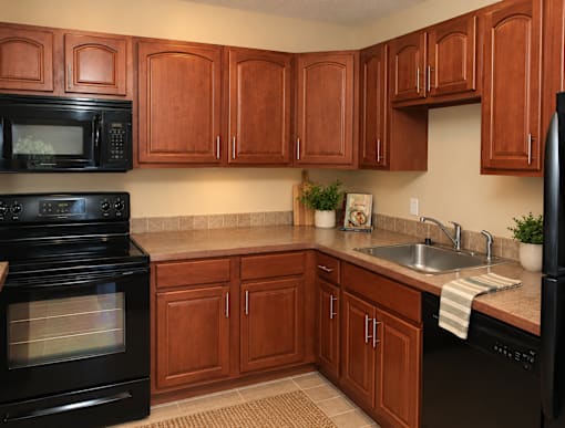 A kitchen with wooden cabinets and black appliances.