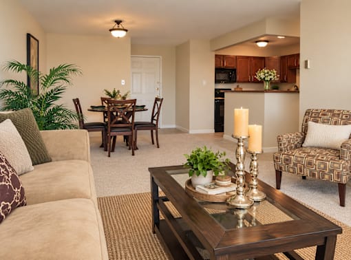 A living room with a brown couch, a wooden coffee table, and a dining table with chairs.