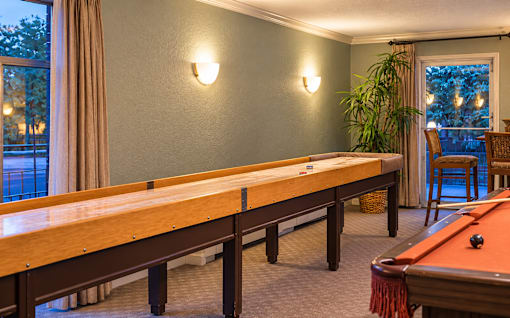 A pool table in a room with a window and a chair.