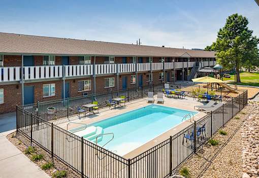 A black fence surrounds a small pool in front of a building.