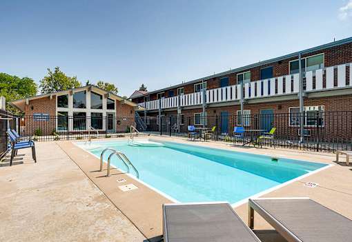A swimming pool surrounded by a fence and chairs.