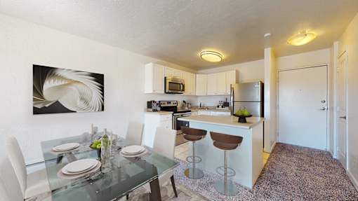 A modern kitchen with a glass dining table set for two.