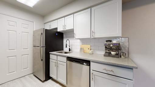 A kitchen with white cabinets and a black refrigerator.