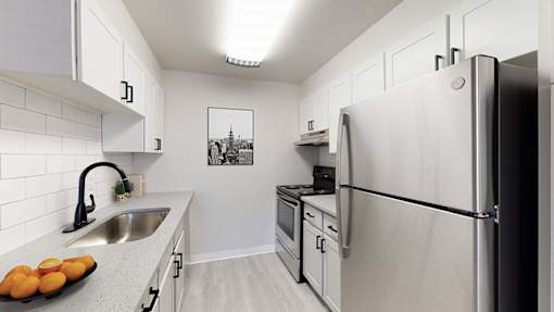 A kitchen with a refrigerator, sink, and oven.