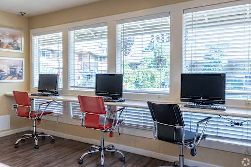 A row of red chairs are in front of a row of computers.