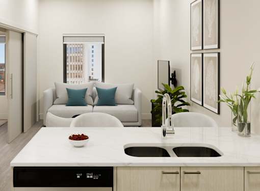 A modern kitchen with a white countertop and a white couch with blue pillows.