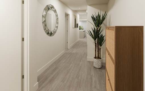 A long hallway with a mirror on the wall and a plant in a planter.