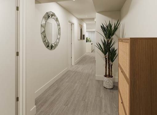 A long hallway with a mirror on the wall and a plant in a planter.