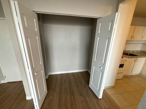 A kitchen with a white door open to a room with a wooden floor.