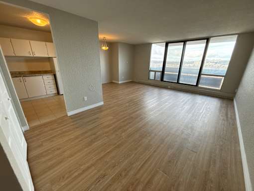 A room with wooden flooring and a large window overlooking a cityscape.