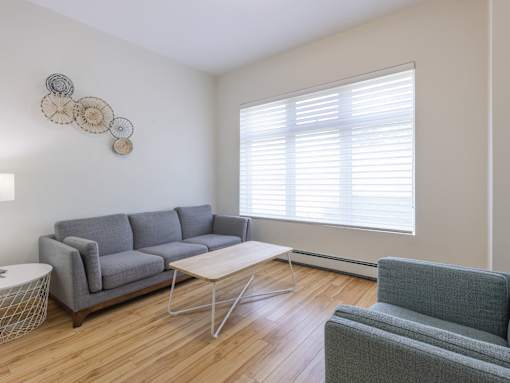 A living room with a grey couch, a white coffee table, and a grey armchair.