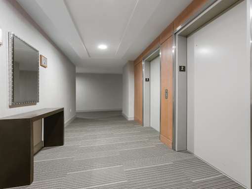 A hallway with a brown door and a mirror on the wall.