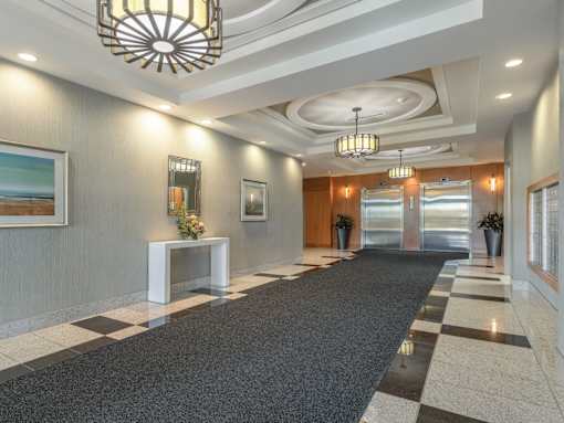 A hallway with a black and white checkered floor and a chandelier hanging from the ceiling.