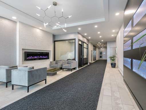 A modern living room with a grey carpet and a fireplace.